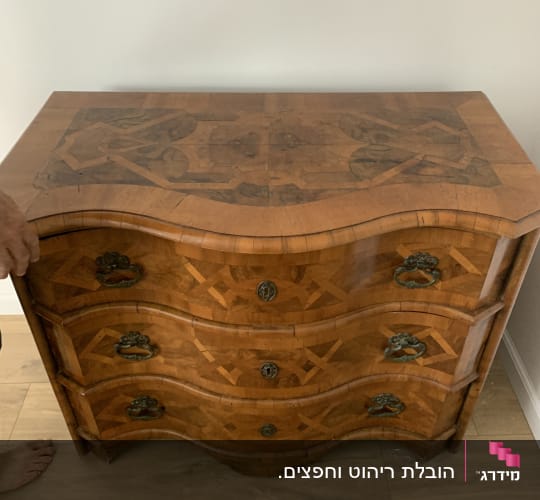שידה מעץ עם ידיות מתכת על רצפת עץ